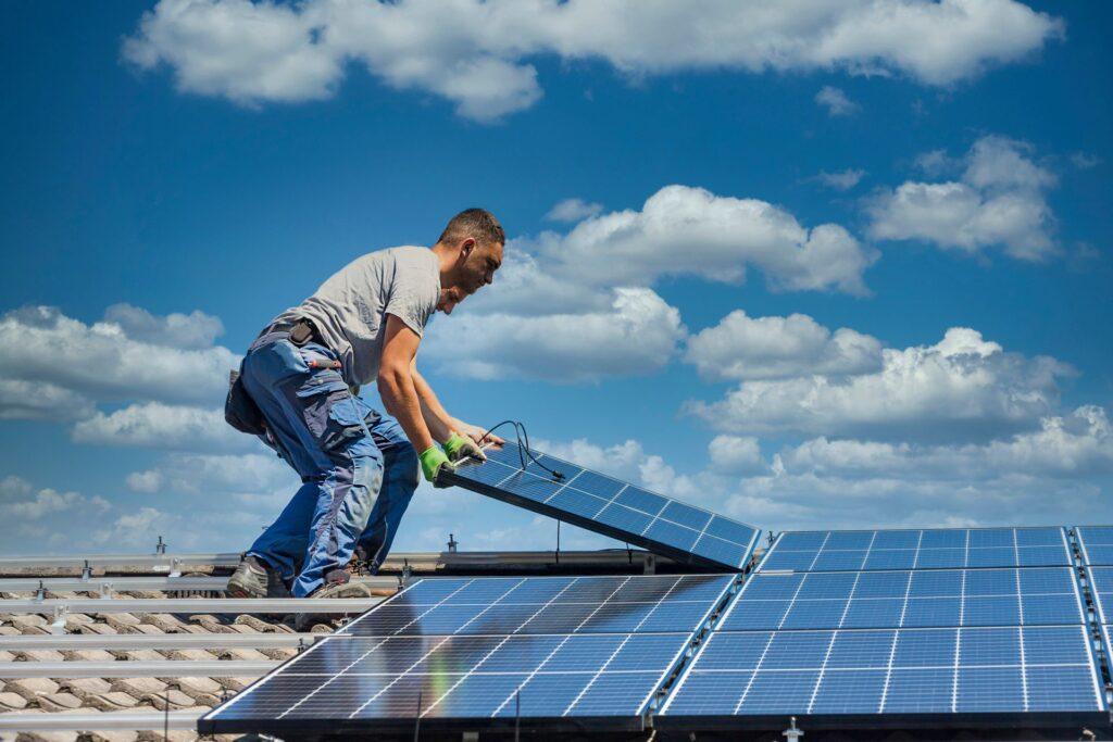 Fachmann bei der Installation von Solarmodulen auf einem Hausdach in Bremen unter blauem Himmel, um erneuerbare Energie durch Photovoltaik zu nutzen.