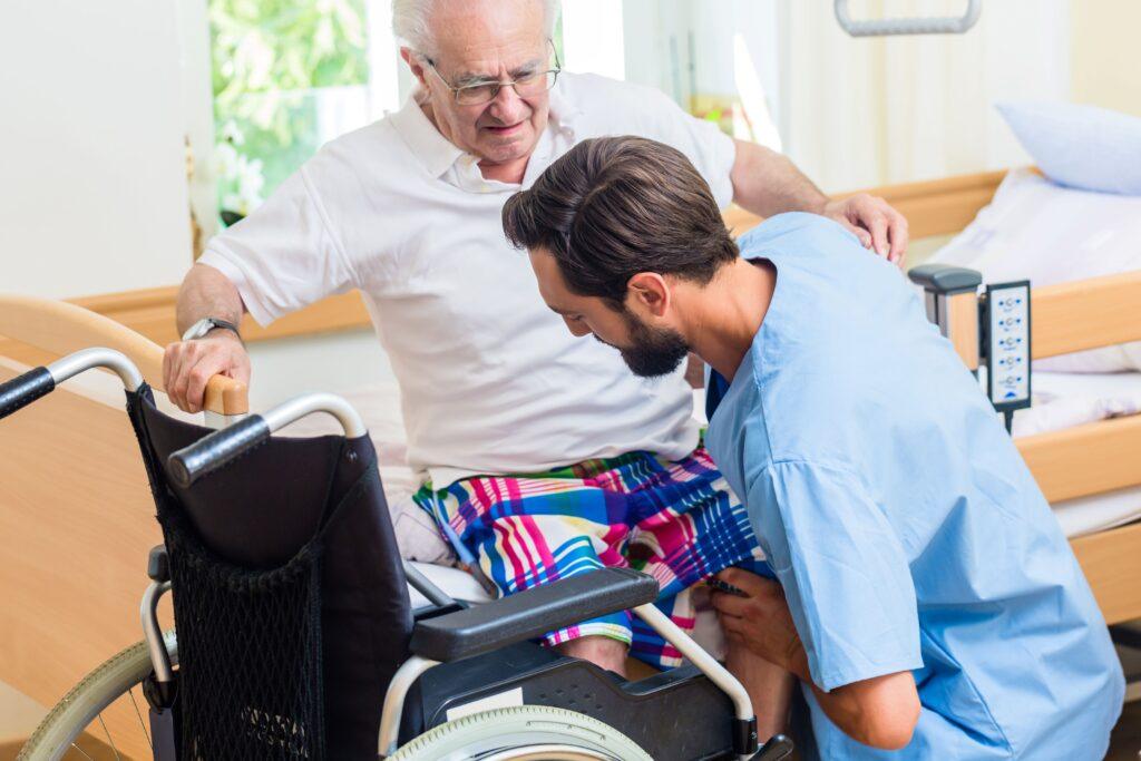 Ein Pfleger hilft einem Patienten aus dem Bett