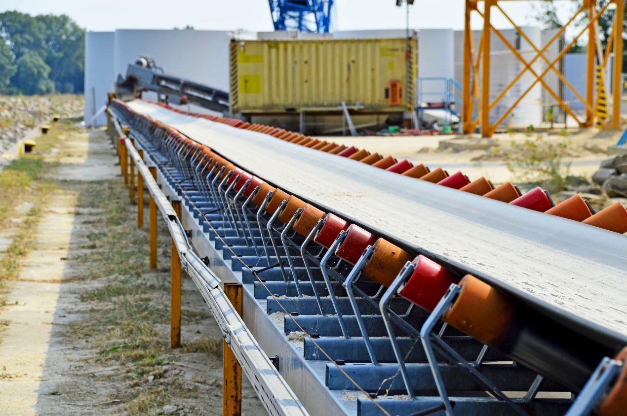  Förderband mit geneigten Kunststoff-Tragrollen auf einer Baustelle im Außenbereich