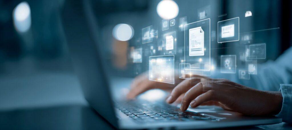 Haende auf Laptop mit digitalen Symbolen fuer Datenmanagement und ML Ops Prozessautomatisierung