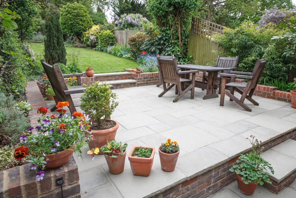 Holzmöbel und bunte Blumen auf gepflegter Terrasse im Garten | Terrassenstühle