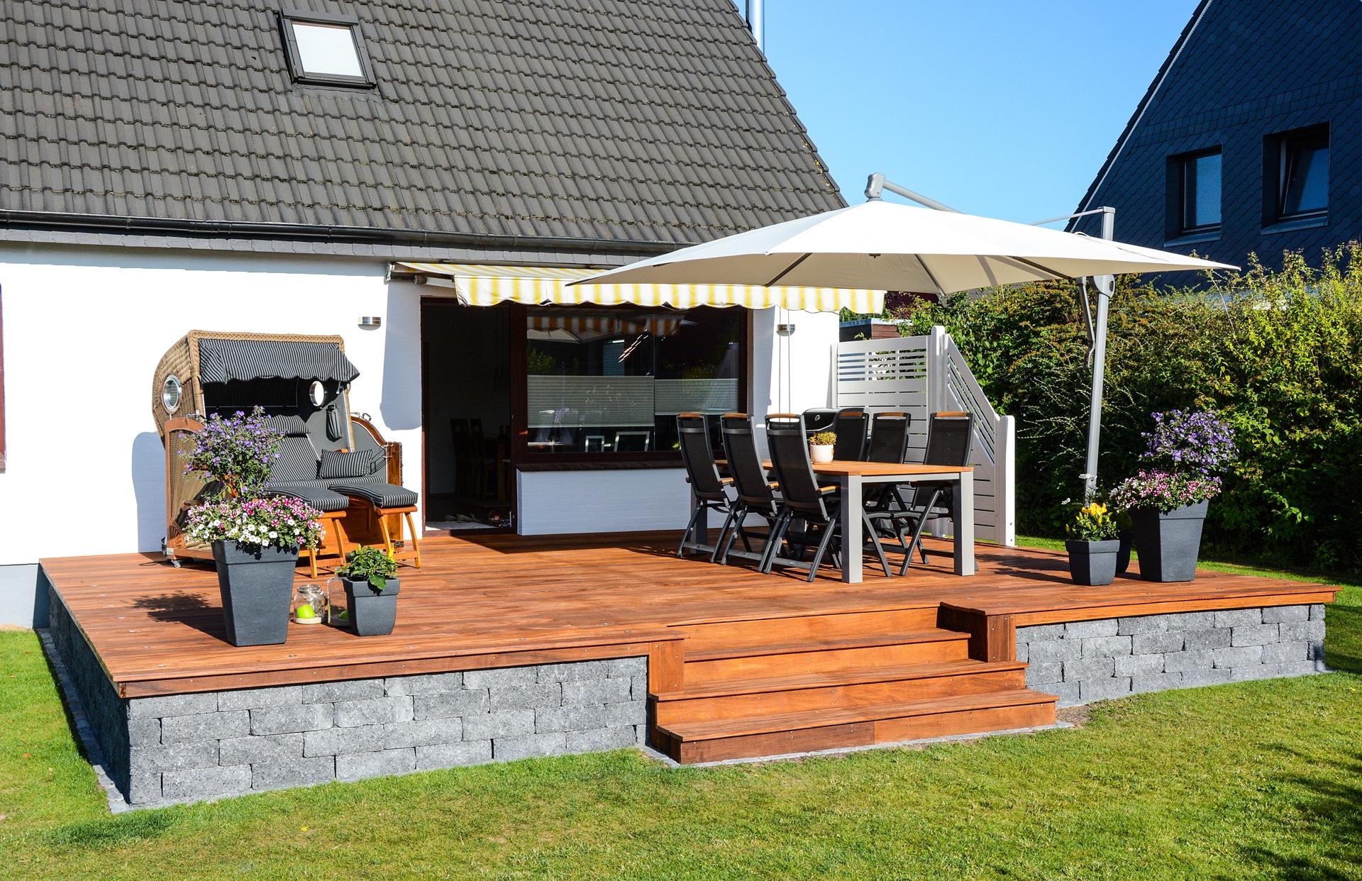 Sonnige Terrasse mit Esstisch, Blumen und großem Sonnenschirm | Terrassenstühle